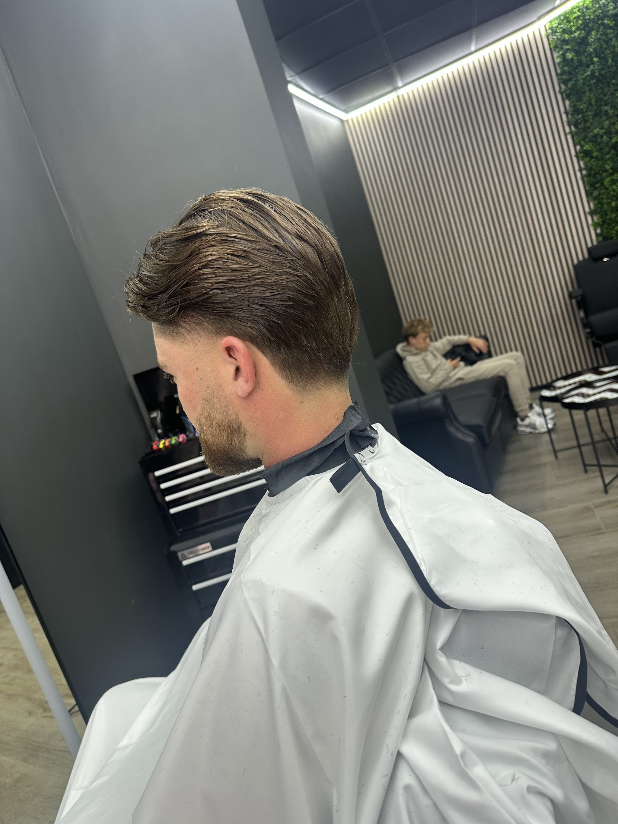 Een net geknipte klant van achteren gezien, strak bijgewerkt in de nek, in de stoel bij Niko’s Barbershop